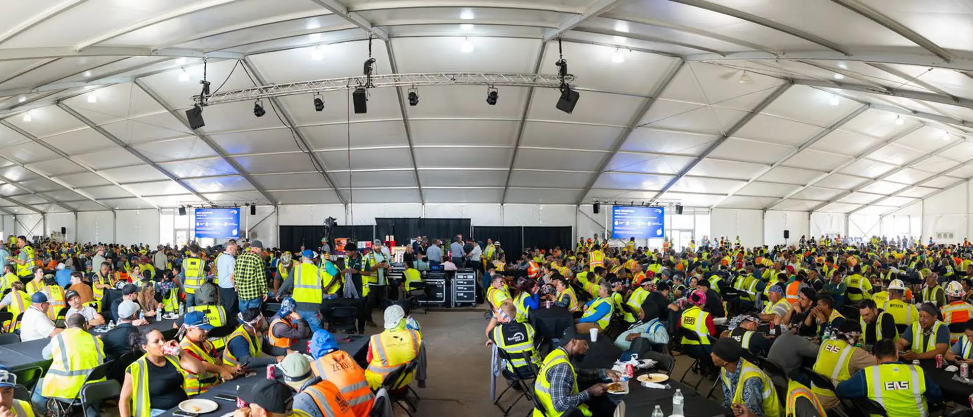 Hundreds of construction workers eating under a clear-span dining structure at a data center site