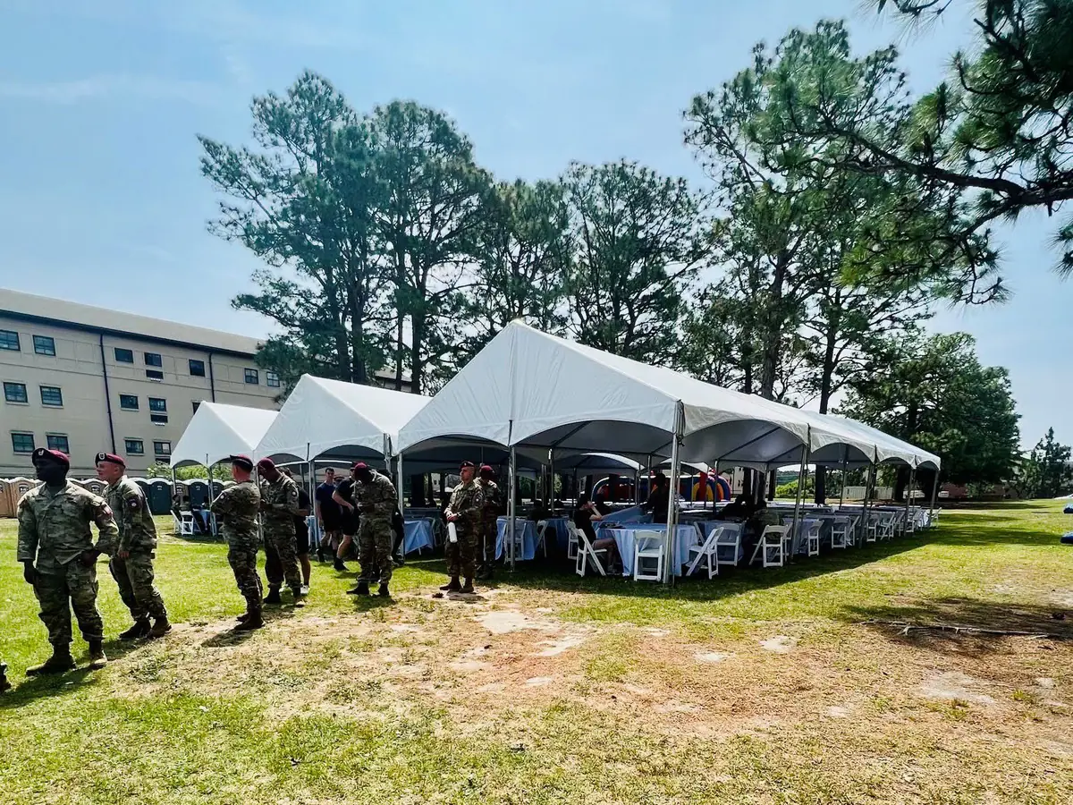 Frame tents and seating set up beside soldiers on an Army installation